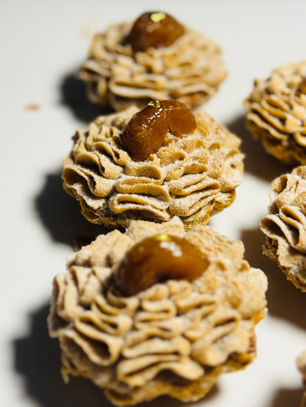 Close-up of Mont Blanc chestnut tart with layered chestnut purée piped in ruffled folds, topped with glazed candied chestnut and gold leaf — L'Œuf Atelier